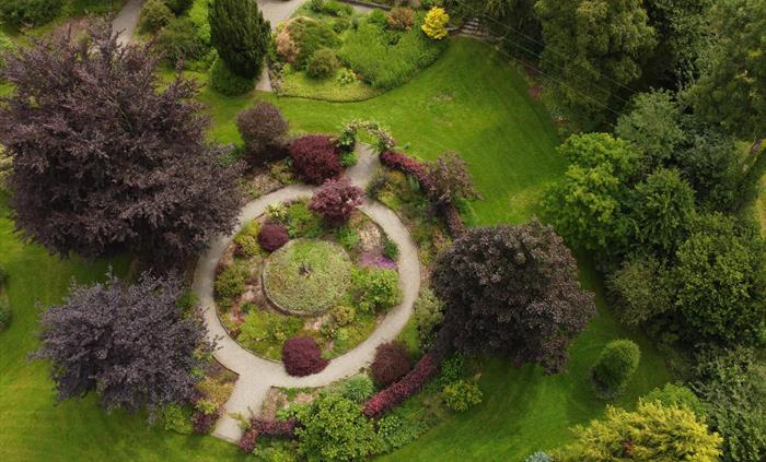 The circular red garden as seen from above, shows the round gravel path with round beds either side of it. The overwhelming colour here is purple foli